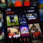 Una persona sostiene un dispositivo con la app de Netflix en una habitación oscura