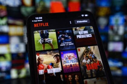 Una persona sostiene un dispositivo con la app de Netflix en una habitación oscura