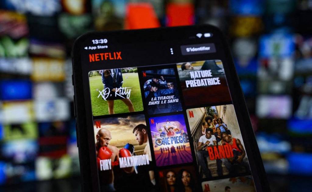 Una persona sostiene un dispositivo con la app de Netflix en una habitación oscura