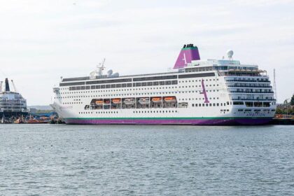 Imagen de un crucero en el mar con pasajeros en la cubierta, algunos de ellos con mascarillas