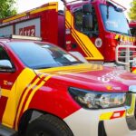Imagen de un camión de bomberos en una calle con humo y daños por incendio