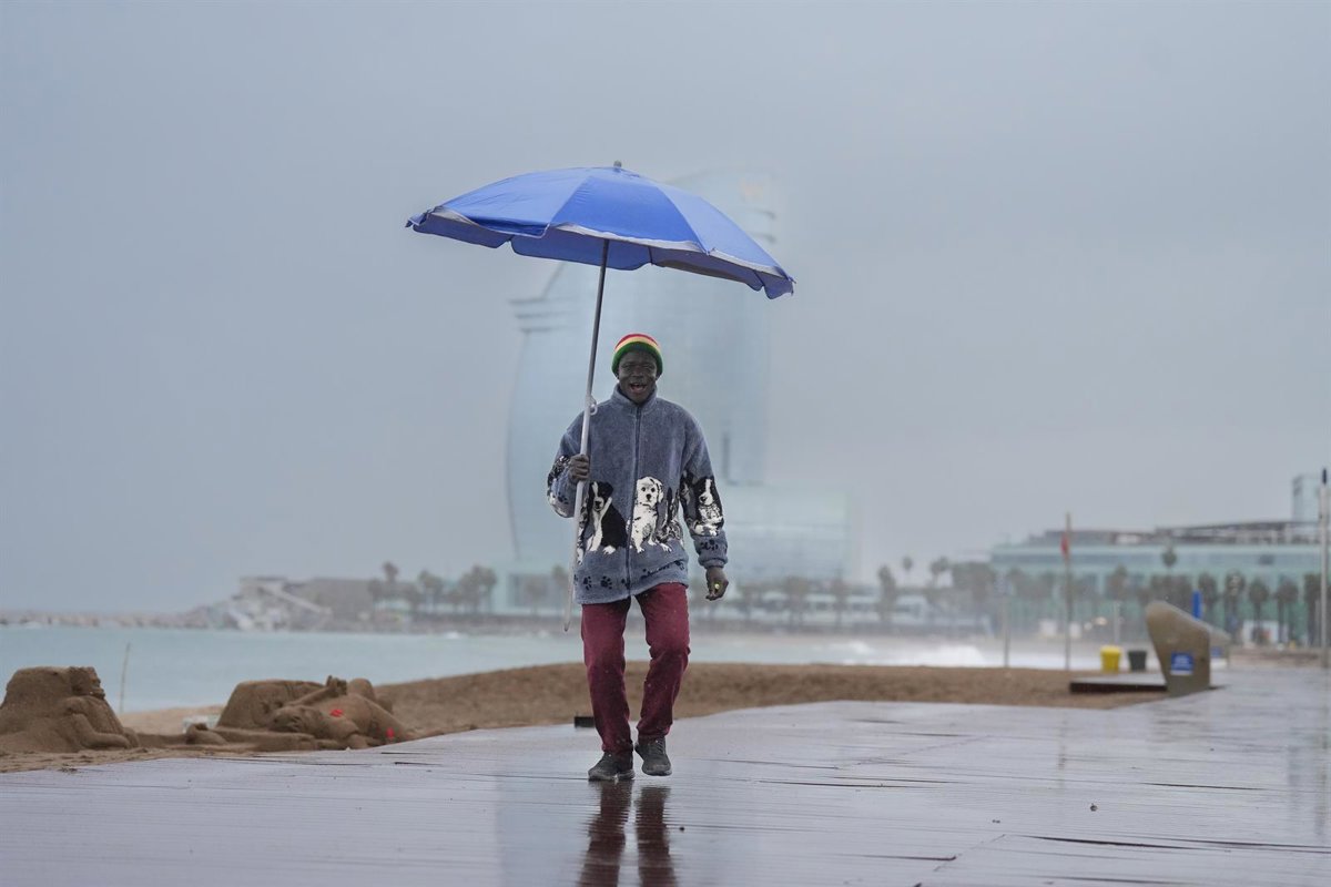 Imagen de lluvias intensas en una calle con paraguas y agua corriendo por la calzada
