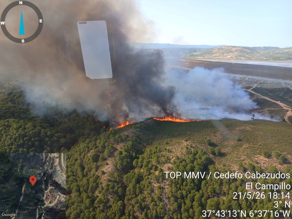 Imagen de un incendio forestal en una zona rural de Málaga, con bomberos trabajando en la extinción