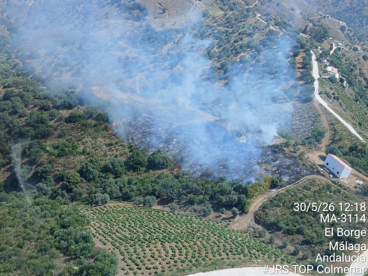 Un camión de bomberos en acción para sofocar un incendio en una zona forestal cerca de Almáchar