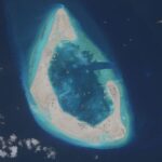 Imagen de un arrecife en el mar de China Meridional transformado en isla con edificios y dragas de succión