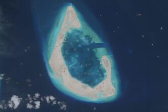 Imagen de un arrecife en el mar de China Meridional transformado en isla con edificios y dragas de succión