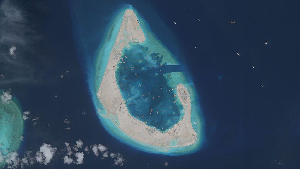 Imagen de un arrecife en el mar de China Meridional transformado en isla con edificios y dragas de succión