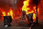 Imagen de una calle de Belfast con vehículos y viviendas dañados por el fuego tras las protestas violentas