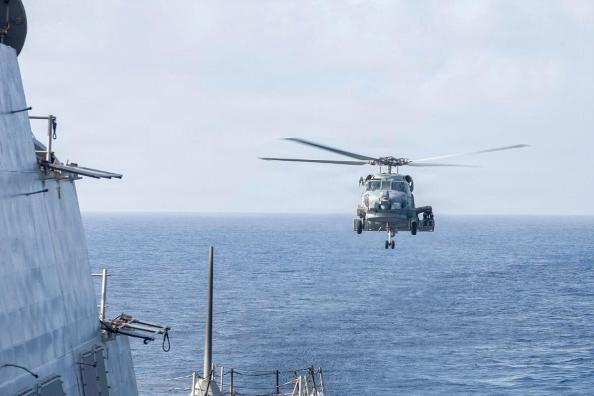 Imagen de una zona militar en el Golfo Pérsico con banderas de EE.UU. e Irán en el fondo, reflejando la tensión en la región