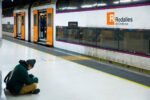 Tren de Rodalies circulando por la vía férrea con un paisaje de fondo
