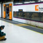 Tren de Rodalies circulando por la vía férrea con un paisaje de fondo