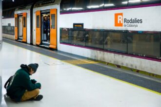 Tren de Rodalies circulando por la vía férrea con un paisaje de fondo