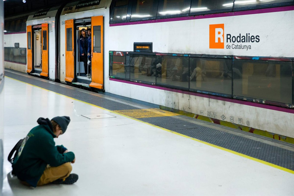 Tren de Rodalies circulando por la vía férrea con un paisaje de fondo