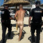Imagen de una playa con gente en la orilla y el mar al fondo, con policías en la arena