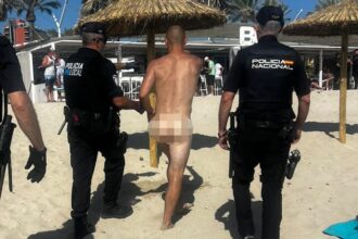Imagen de una playa con gente en la orilla y el mar al fondo, con policías en la arena