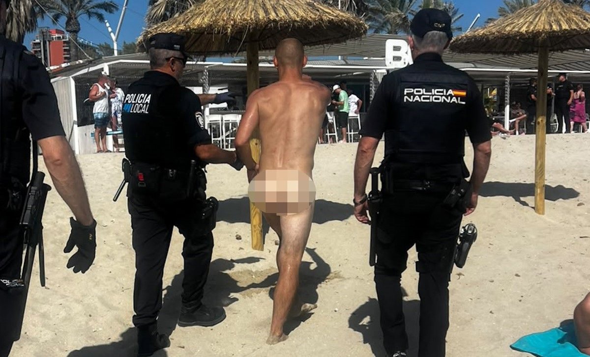 Imagen de una playa con gente en la orilla y el mar al fondo, con policías en la arena