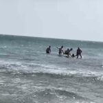 Imagen de un hombre siendo rescatado del mar por agentes de la Policía Nacional
