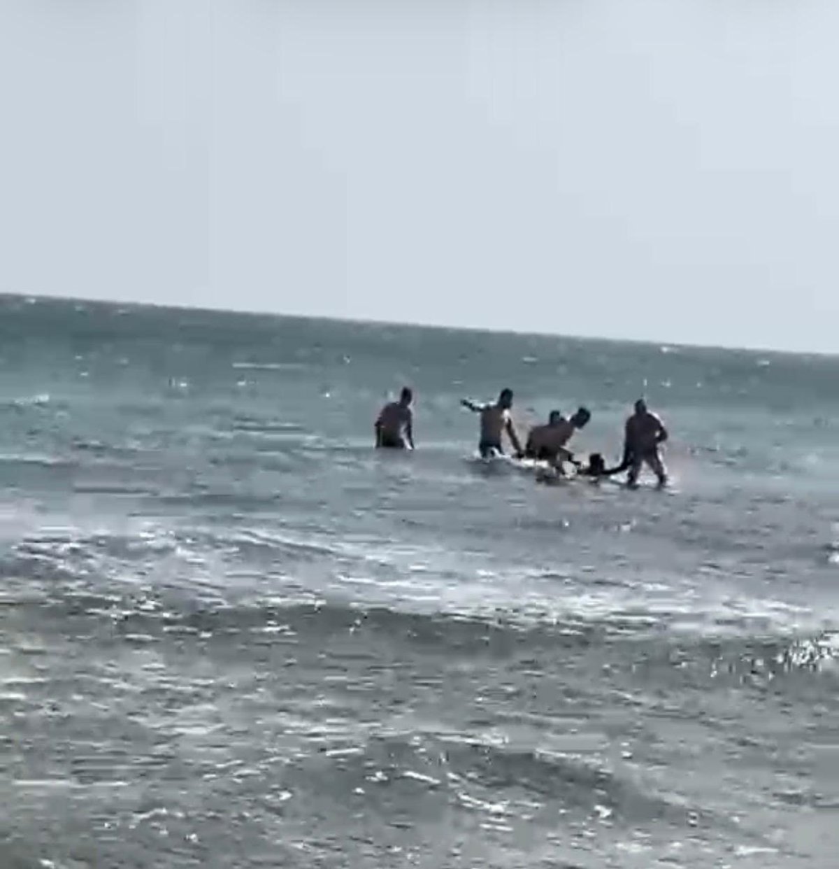 Imagen de un hombre siendo rescatado del mar por agentes de la Policía Nacional