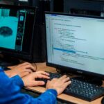 Profesionales en capacitación tecnológica frente a pantalla con datos de déficit de talento TI en Colombia