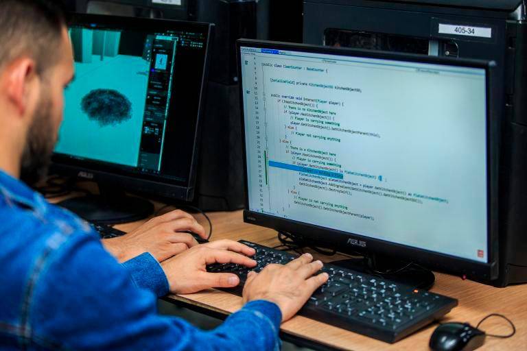 Profesionales en capacitación tecnológica frente a pantalla con datos de déficit de talento TI en Colombia